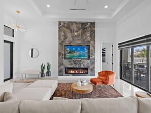 Relax in a spacious living room with a large flat-screen TV, fireplace, and comfortable seating area.