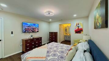 Een slaapkamer met een bed, een dressoir, een televisie en kunstwerken aan de muren.
