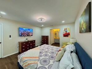 Une chambre à coucher comprenant un lit, une commode, un téléviseur et des œuvres d’art accrochées aux murs.
