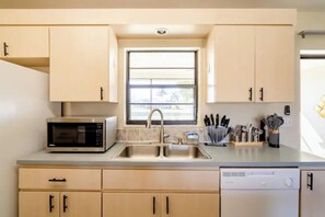 A modern kitchen with a built-in microwave, stainless steel sink, and a dishwasher.