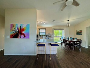 A modern kitchen with a bar area, dining table, and chairs.