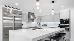 Una cocina moderna con una isla grande, electrodomésticos de acero inoxidable y taburetes negros.