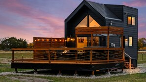 A modern cabin with a wooden deck and a large window. - Modern Tiny Cabin, with Hot tub in Choteau MT (Choteau)