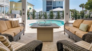 A poolside area with wicker furniture and a view of a building complex.