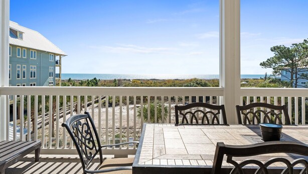 A balcony with a view of the beach and ocean, featuring a table and chairs. - Gulfisde Escape: Beachfront Condo in Indian Pass, Community Pool, Pet Friendly (Cape San Blas)