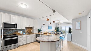 A modern kitchen with white cabinets, a granite countertop, and a central island. - Gulfisde Escape: Beachfront Condo in Indian Pass, Community Pool, Pet Friendly (Cape San Blas)