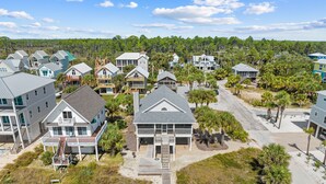 A coastal residential area with houses featuring balconies and a wooden walkway leading to the beach.