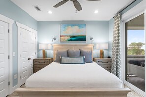 Een slaapkamer met een bed, een plafondventilator, een schilderij en uitzicht door een raam.