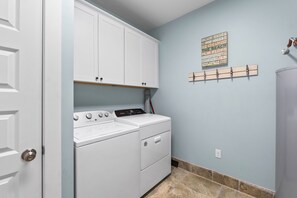 A laundry room with a white washer and dryer, a blue wall, and a word cloud decoration. - TipSea Turtle: 4th of July week now available as a Friday or Saturday check in! (Cape San Blas)