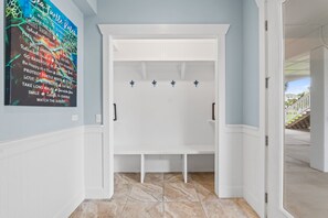 A hallway with a white bench, a wall-mounted towel rack, and a poster with text. - TipSea Turtle: 4th of July week now available as a Friday or Saturday check in! (Cape San Blas)