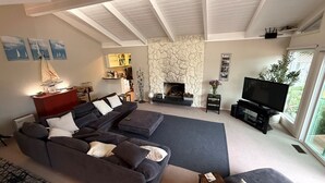 Un salon moderne avec un canapé d’angle, une cheminée, un téléviseur et un mur décoratif en pierre.