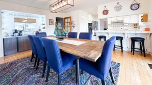 Une cuisine moderne avec des meubles blancs, un îlot central en bois et un coin repas avec des chaises bleues et une table en bois.