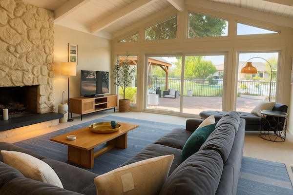 Sunlit living room framed by soaring ceilings & garden views