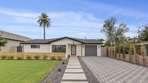 A modern house with a paved driveway, a front lawn, and a palm tree. - This Must Be The Place ! (Phoenix)