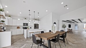 A modern kitchen with white cabinets, a wooden dining table, and black chairs. - This Must Be The Place ! (Phoenix)