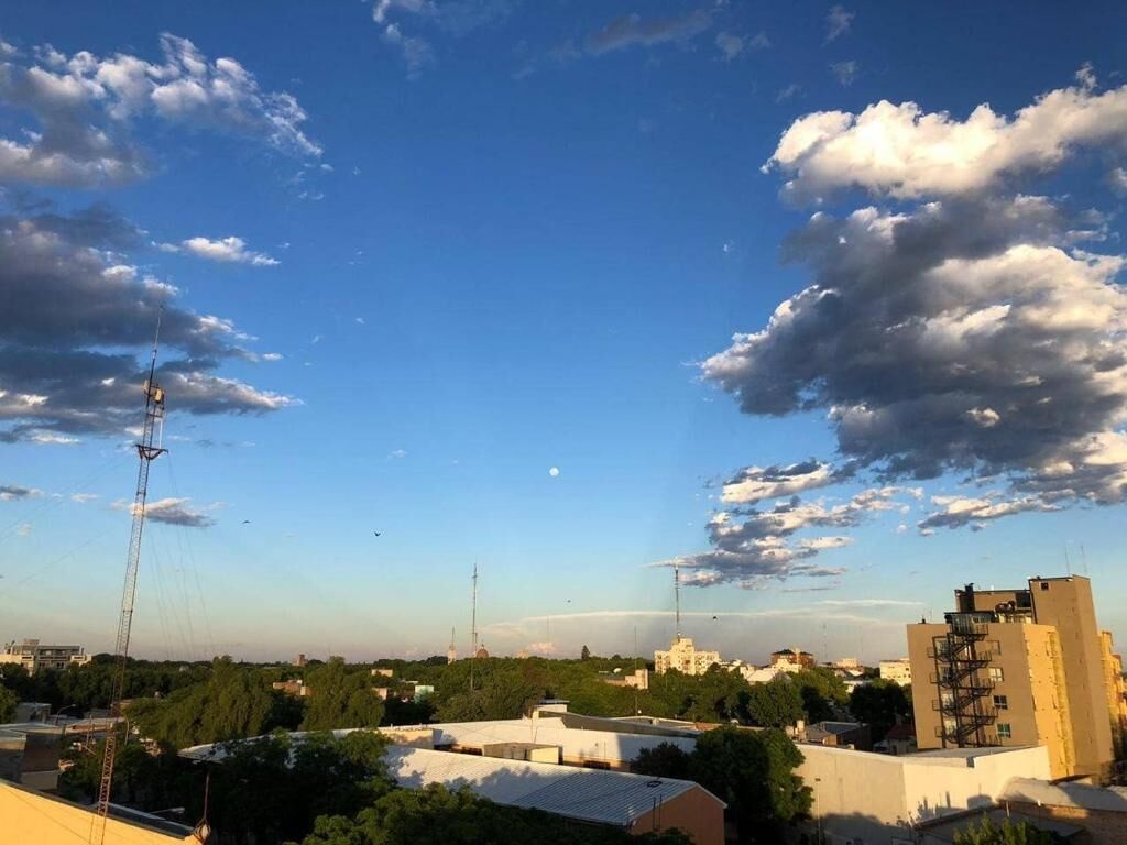 A cityscape with buildings, a clear sky, and scattered clouds.
