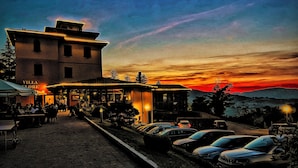A building with a sign 'VILLA GLORIE' and a paved area with parked cars. - Villa Clorè Hotel & Spa (Lama Mocogno)