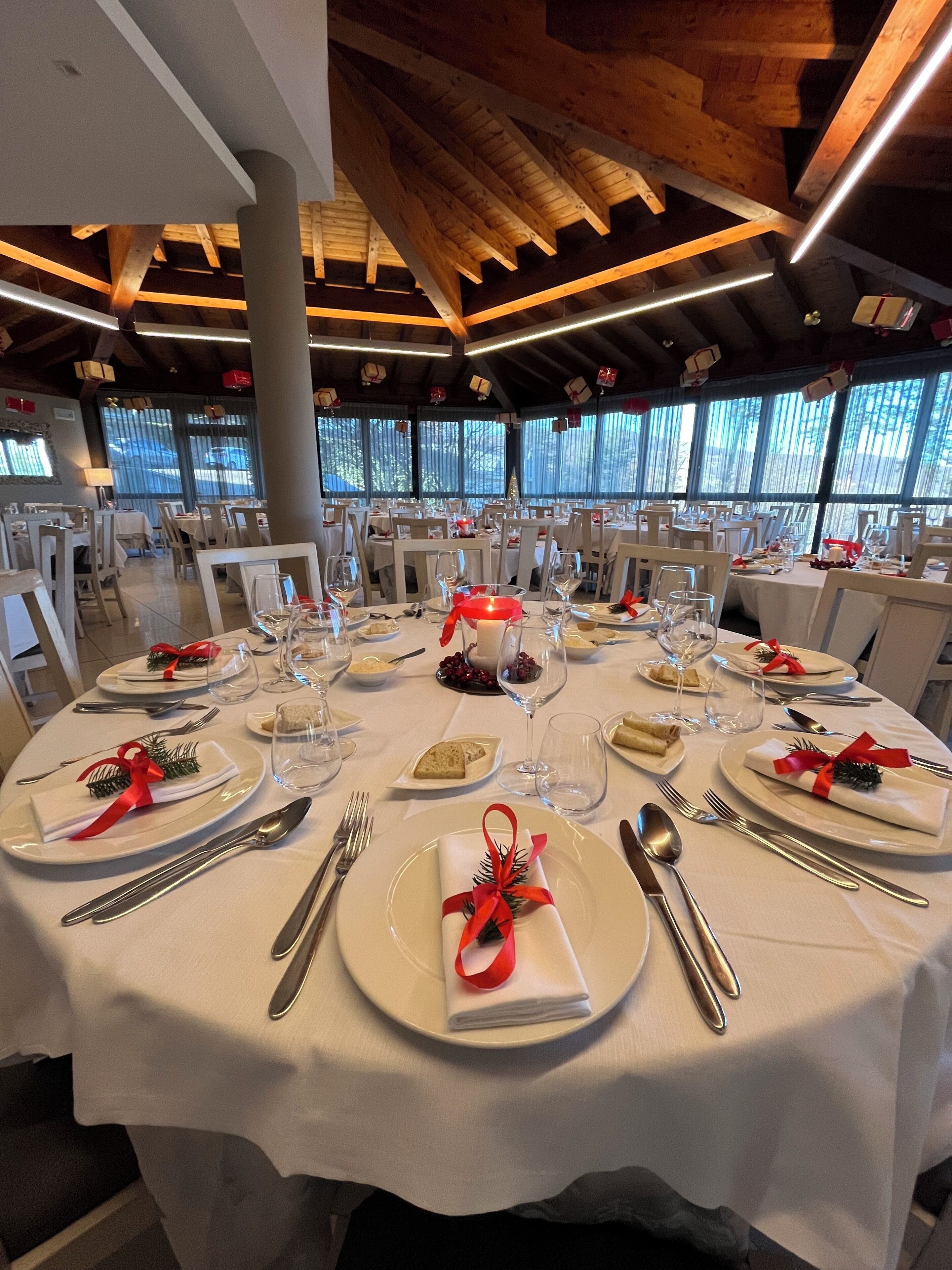 A round dining table with white tablecloths, neatly set with plates, cutlery, and glasses.