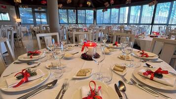 A round dining table with white tablecloths, neatly set with plates, cutlery, and glasses.