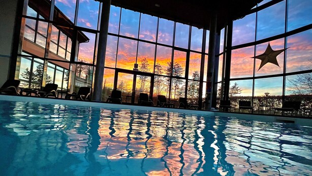 An indoor swimming pool with clear reflections, large windows, and a star decoration. - Villa Clorè Hotel & Spa (Lama Mocogno)