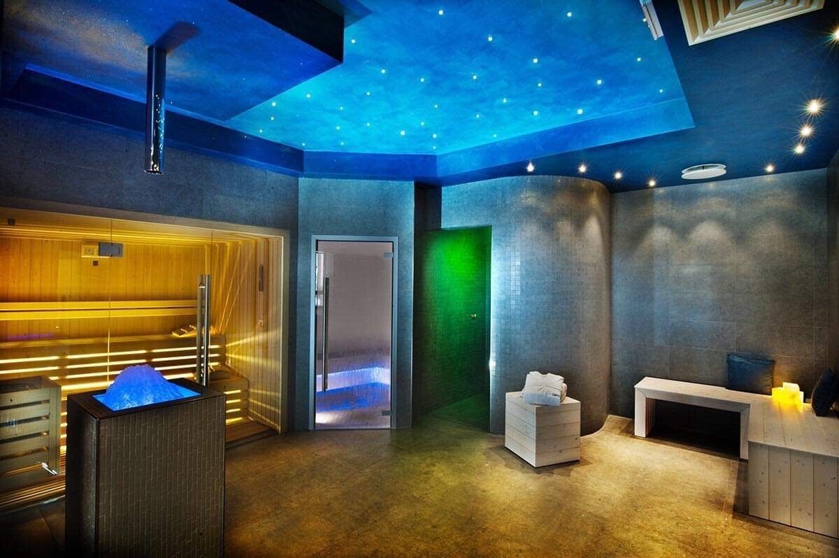 Un cuarto de spa con sauna, camilla de masaje y mostrador de recepción.