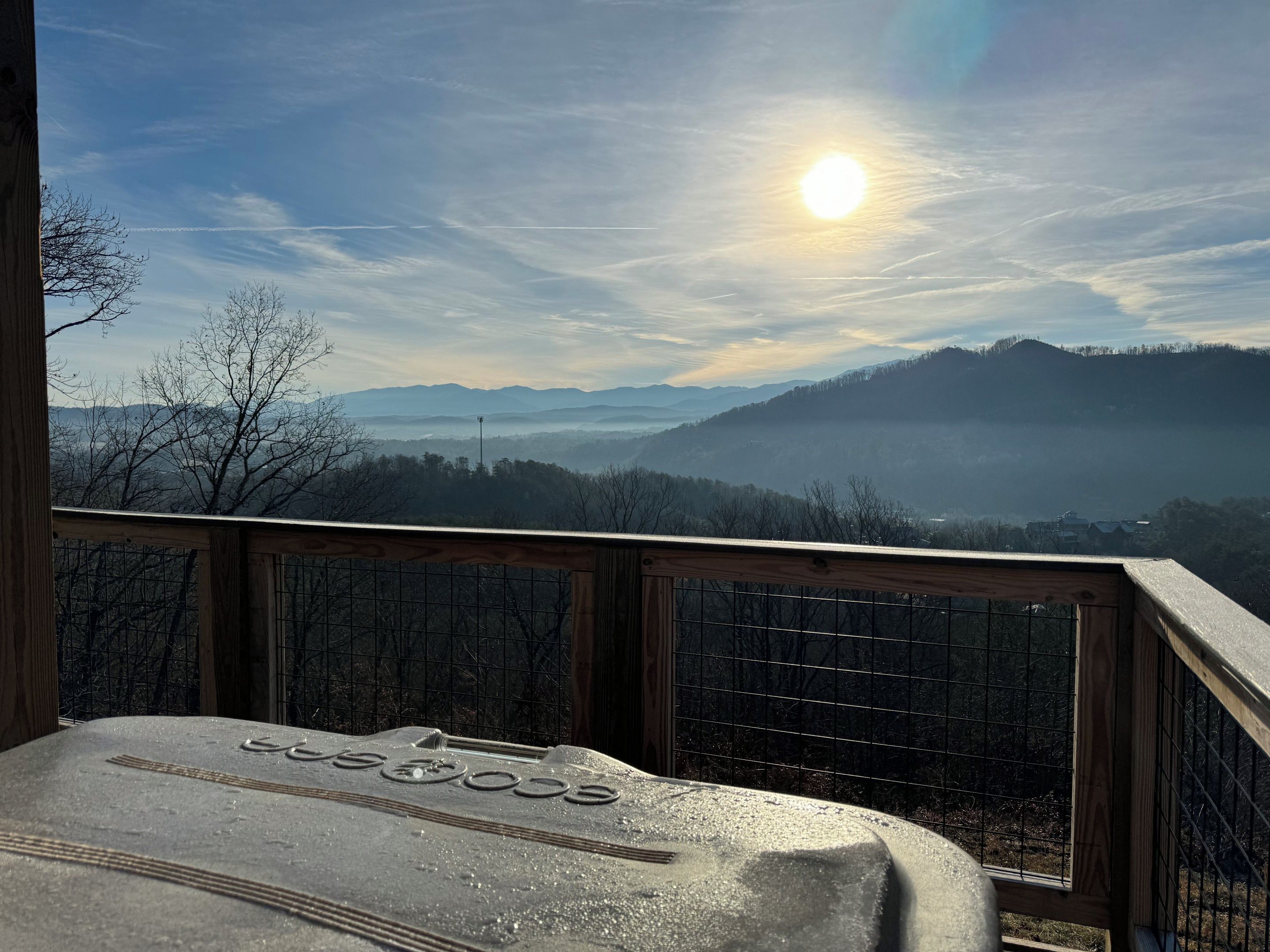 A wooden deck with a metal railing overlooking a mountainous landscape.