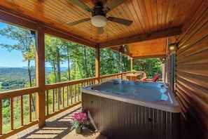 A wooden deck with a hot tub, wooden railings, and a view of a forested landscape. - Stunning Mtn Views, Hot Tub+Fire Pit, WiFi, Grill! (Bakersville)