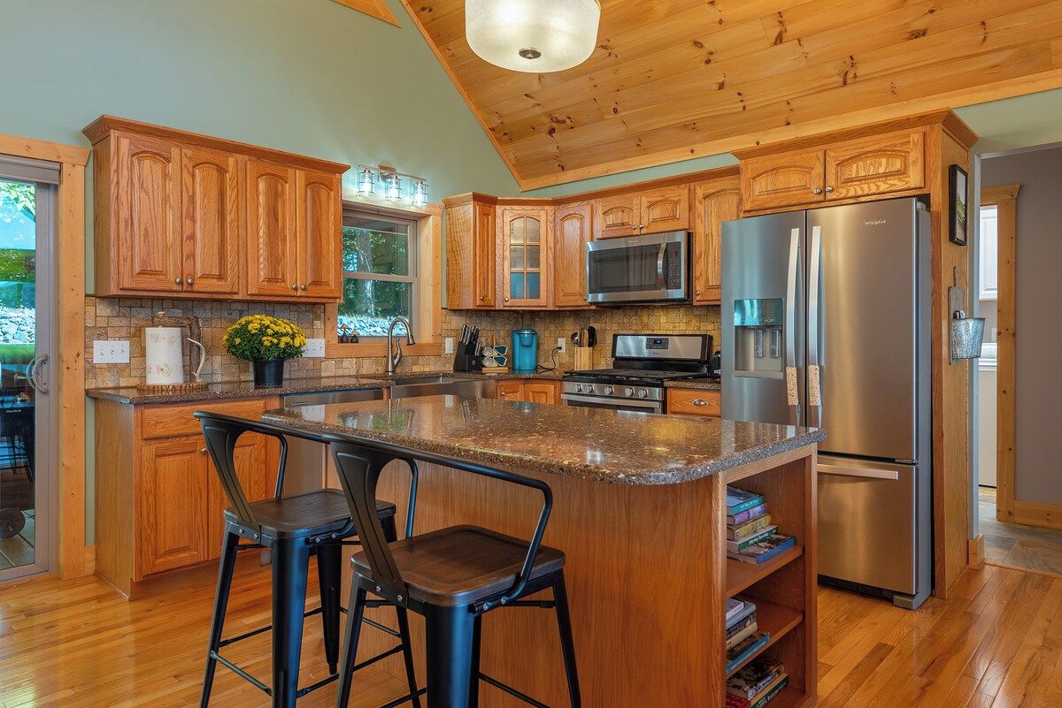 A kitchen with wooden cabinets, a stainless steel refrigerator, and a granite countertop.