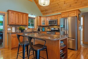 A kitchen with wooden cabinets, a stainless steel refrigerator, and a granite countertop. - Stunning Mtn Views, Hot Tub+Fire Pit, WiFi, Grill! (Bakersville)
