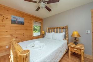 A wooden room with a bed, a ceiling fan, a window, and a wooden headboard. - Stunning Mtn Views, Hot Tub+Fire Pit, WiFi, Grill! (Bakersville)