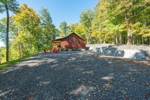 A cabin with a gravel driveway, surrounded by trees. - Stunning Mtn Views, Hot Tub+Fire Pit, WiFi, Grill! (Bakersville)