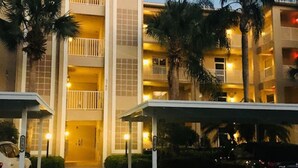 A multi-story hotel with a central atrium, balconies, and covered parking areas. - Top Floor Condo with Panoramic View of Golf Course & Lake (Naples)