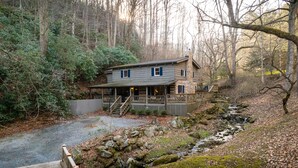 A cabin with a deck, surrounded by trees and a stream. - Blue Ridge Cabin with Modern Farmhouse Decor on Private Stream  (Banner Elk)