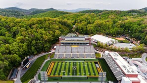 Surrounded by lush greenery, this sports complex offers a football field and modern facilities, including a covered seating area and a sports administration building.