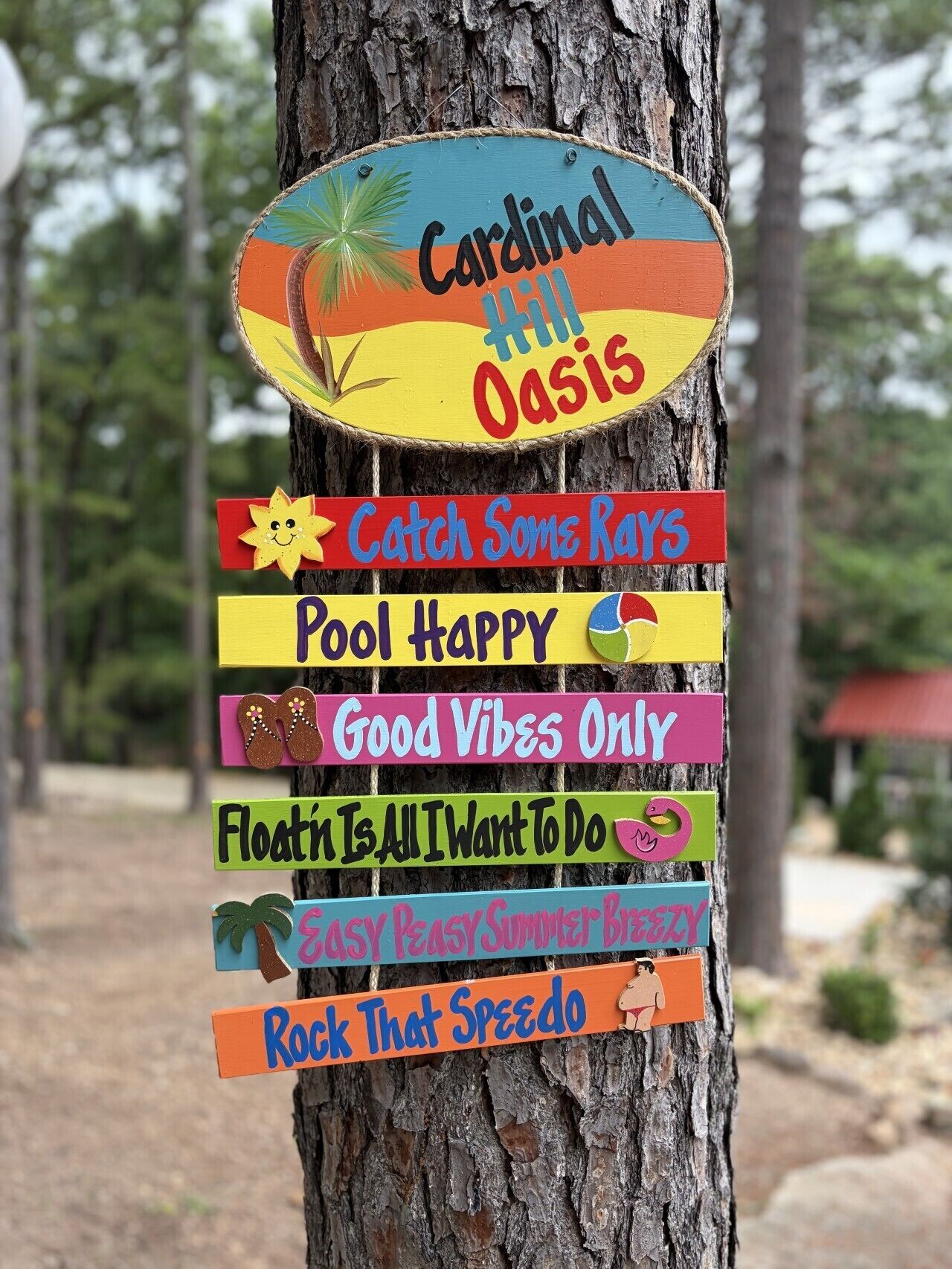 A wooden sign with multiple colorful panels, each with a different message, attached to a tree.