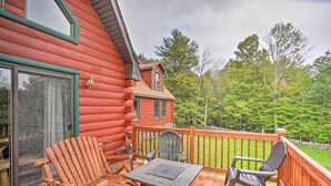 A wooden deck with Adirondack chairs and a table, overlooking a forested area. - Grand Windham Retreat w/ Fire Pit & Game Room (Windham)