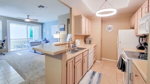 A modern kitchen with a central island, a dining area with a sofa, and a view of the outdoors. - Private North Scottsdale Condo - Pool, Spa, Sauna & Outdoor Kitchen (Scottsdale)