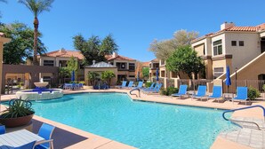 A pool area with lounge chairs and a fountain, surrounded by buildings with red-tiled roofs. - Private North Scottsdale Condo - Pool, Spa, Sauna & Outdoor Kitchen (Scottsdale)
