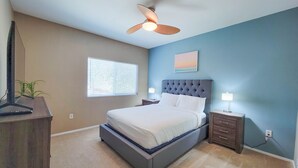 A bedroom with a bed, a ceiling fan, a window with blinds, a nightstand, a lamp, and a wall-mounted painting. - Private North Scottsdale Condo - Pool, Spa, Sauna & Outdoor Kitchen (Scottsdale)