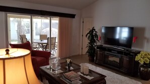 Un salon comprenant un canapé, une table basse, un téléviseur et un coin repas avec une table et des chaises.