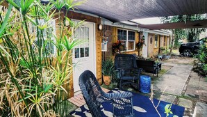 Un patio couvert aménagé avec des meubles en osier, un paillasson et des plantes en pot.