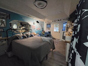 A bedroom with a bed, a dresser, and a window. - Island Parlor Inn Coastal Mid Century Studio (Savannah)