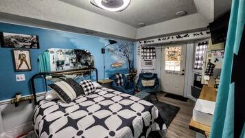 Une chambre avec un lit superposé, un bureau avec une chaise, une coiffeuse avec un miroir et une porte sur laquelle est affiché un panneau « Bienvenue ».