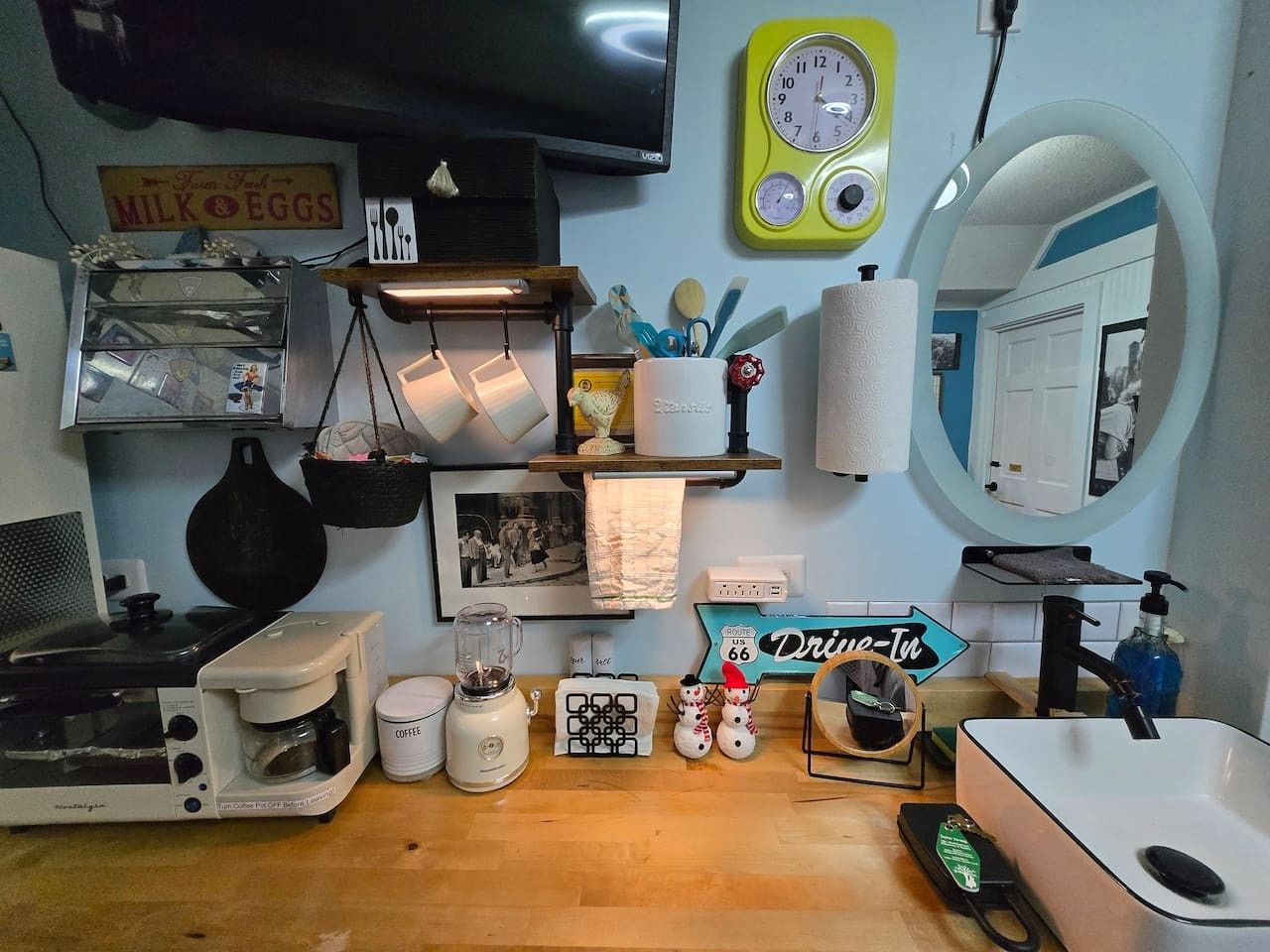 A kitchen with a coffee maker, a blender, a toaster, and a clock on the wall.