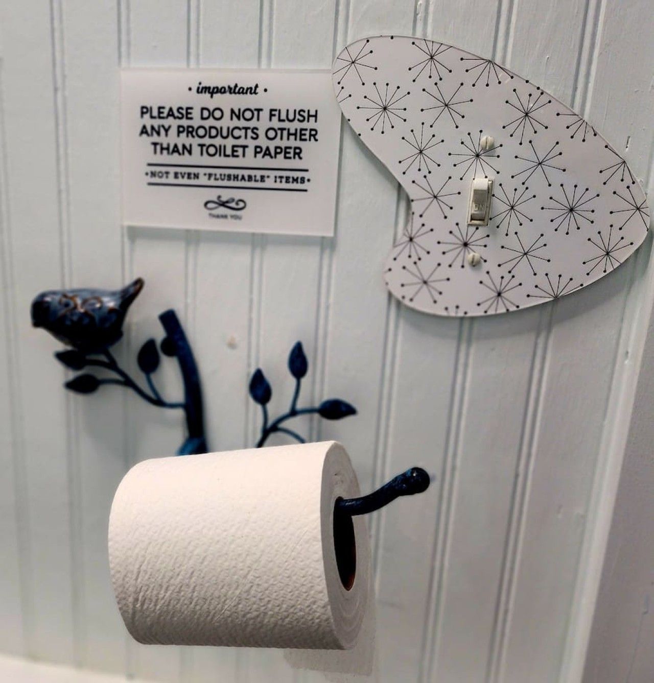 Un rouleau de papier toilette fixé au mur, accompagné d’un panneau indiquant qu’il ne faut jeter dans les toilettes que du papier toilette.