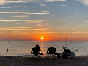 A beach scene with a sunset, two chairs, and fishing rods. - Island Parlor Inn Coastal Mid Century Studio (Savannah)