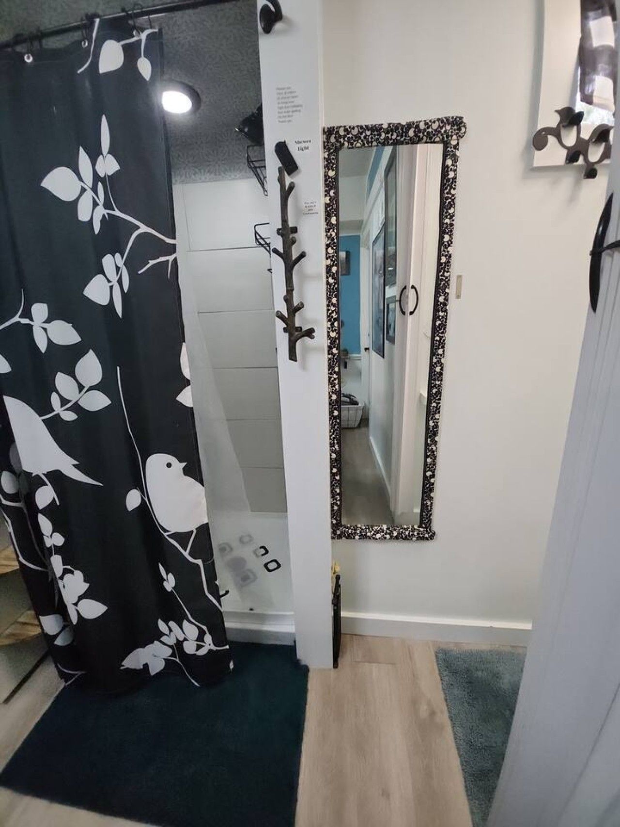 A bathroom with a shower curtain, a mirror, and a tiled wall.