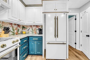 A kitchen with white cabinets, a blue stove, and a white refrigerator.
