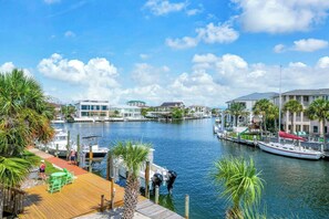 A marina with boats docked, a wooden deck with chairs, and buildings in the background. - Seahab *Waterfront Dock* Private Beach Access! (Destin)