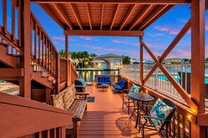 A wooden deck with outdoor furniture, a pool, and a view of a residential area.
